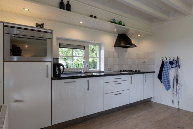 Moderne Kueche im Ferienhaus het Assenhoekje, Den Ham, Twente. Vollstaendig ausgestatteter Innenraum mit Blick auf die gruene Umgebung.