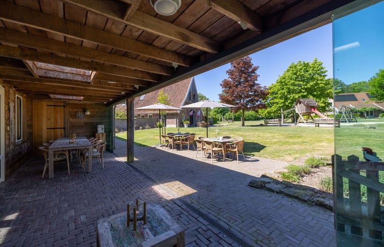 Gemuetliches Wohnzimmer im Ferienhaus in de Lutte, Twente, mit buntem Sofa, Holzofen und grossem Esstisch fuer einen komfortablen Aufenthalt.