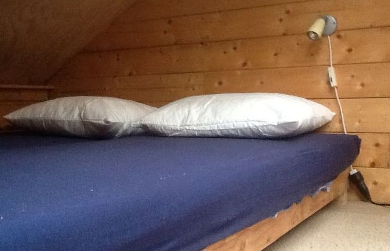 Gemuetliches Schlafzimmer im Ferienhaus in De Lutte in Twente mit Holzwaenden und bequemem Bett in Overijssel.