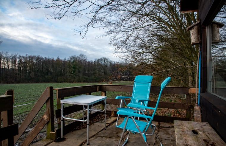 Terrasse des Ferienhauses in De Lutte in Twente mit Sitzgelegenheit und Blick auf gruene Felder in Overijssel.