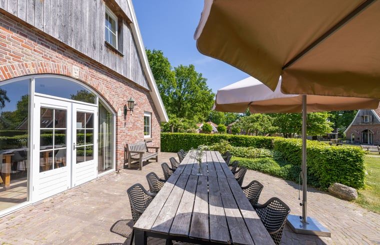 Gemuetlicher Eingang zum Ferienhaus in de Lutte, Twente, mit einem bakfiets auf der gruenen Wiese, ideal fuer einen erholsamen Aufenthalt in Overijssel.