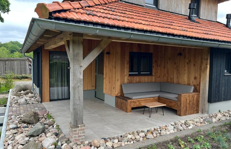 Gemuetliche ueberdachte Terrasse des Ferienhauses in de Lutte, Twente, Overijssel mit Holzbank.