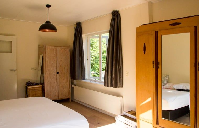 Attraktives Schlafzimmer im Ferienhaus in De Lutte, Twente, mit Holzmoebeln und Blick auf die gruene Umgebung von Overijssel.