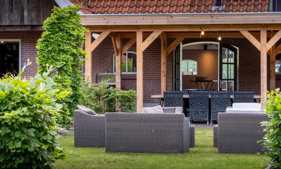 Veranda und Sitzecke im Ferienhaus Landgoed Nieuwhuis in Ootmarsum, Twente, umgeben von Gruenanlagen.