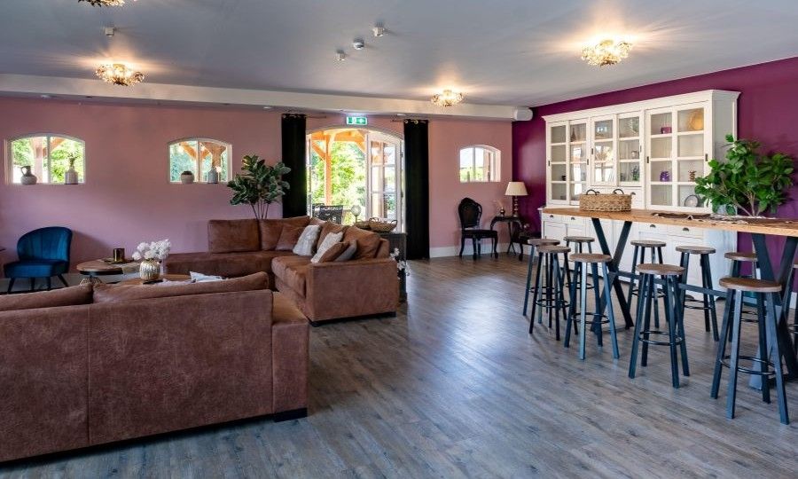 Geraeumiges Wohnzimmer im Ferienhaus Landgoed Nieuwhuis in Ootmarsum, Twente, mit bequemen Sofas und Bar.