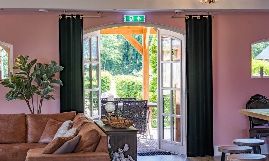 Offene Tueren zur Terrasse vom Wohnzimmer im Ferienhaus Landgoed Nieuwhuis in Ootmarsum, Twente.