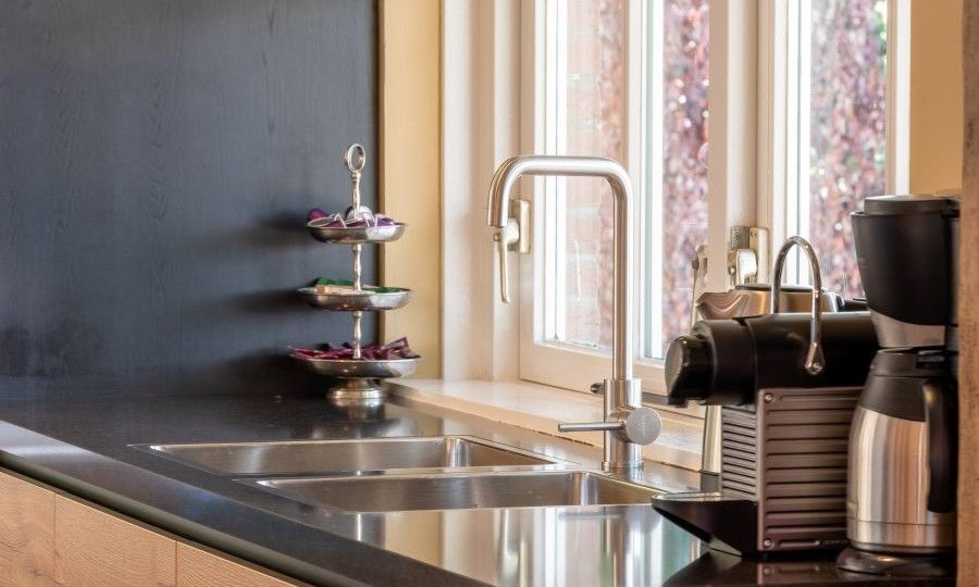 Kueche mit modernen Geraeten im Ferienhaus Landgoed Nieuwhuis in Ootmarsum, Twente, mit Blick auf den Garten.