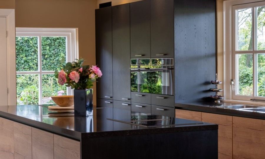 Stilvolles Esszimmer im Ferienhaus Landgoed Nieuwhuis in Ootmarsum, Twente, mit Holztischen und roten Stuehlen.