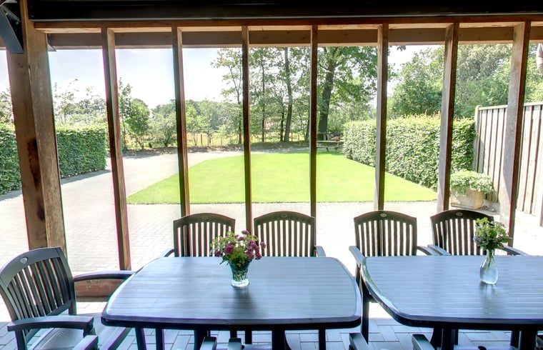 Veranda van vakantiehuisje in Hezingen met uitzicht op groene omgeving in Twente, Overijssel.