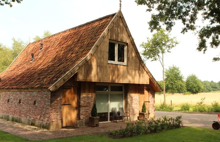 Cottage in Hezingen, ein charmantes Ferienhaus in Twente, Overijssel mit rustikaler Fassade und gruener Umgebung.