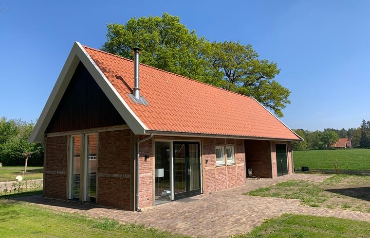 Ferienhaus in Beuningen, Twente mit roten Dachziegeln und gruener Umgebung in Overijssel.