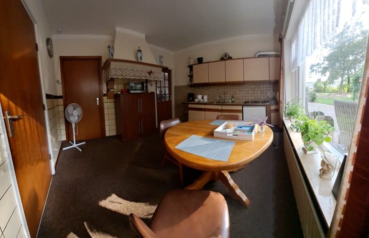 Gezellige eetkamer in Huisje in Beuningen, vakantiehuis in Twente, Overijssel, met uitzicht op de groene omgeving.