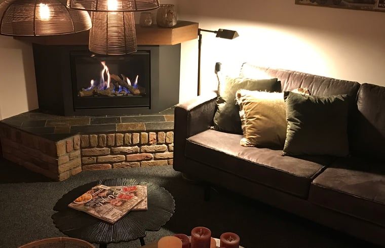 Gemuetliches Wohnzimmer im Cottage in Weerselo, Twente mit Kamin und bequemem Sofa.