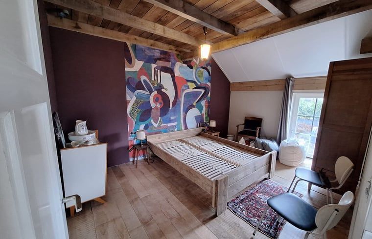 Gemuetlicher Innenraum des Ferienhauses in Tilligte, Twente, mit authentischen Holzbalken und einem stimmungsvollen Holzofen.