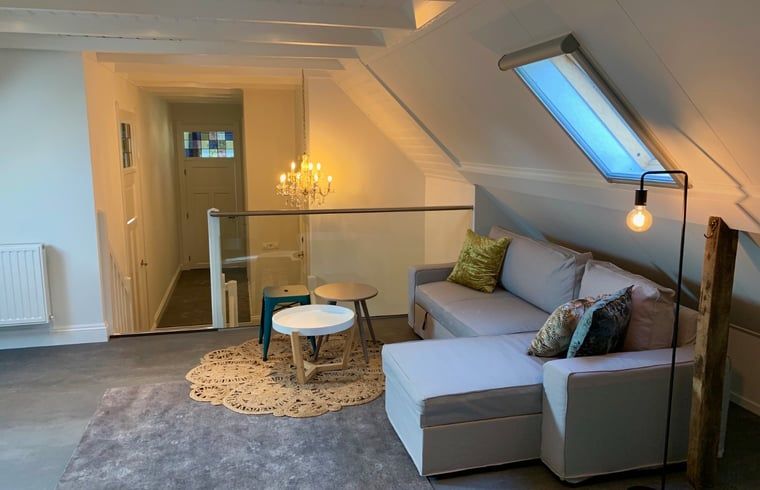 Gezellige zolderruimte in Vakantiehuis in Reutum, Twente, Overijssel met comfortabele bank.
