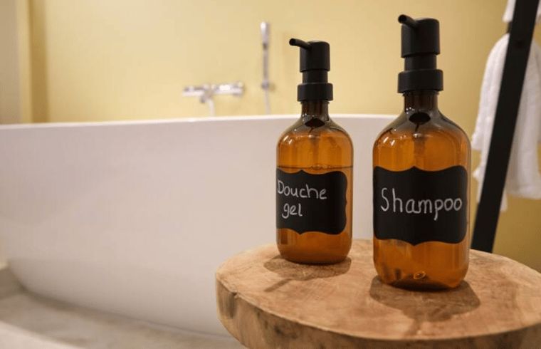 Luxury bathroom in Cottage in Reutum, vacation home in Twente, Overijssel, with stylish shower gel and shampoo next to a modern bathtub.