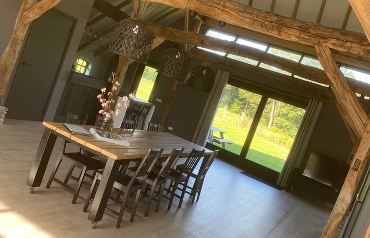 Stijlvolle eetruimte in Vakantiehuisje Ambt Delden, Twente met houten tafel en uitzicht op de natuur.