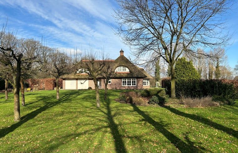Cottage in Rossum, ein Ferienhaus in Twente, Overijssel, umgeben von einem gruenen Garten und einem Waldgebiet.