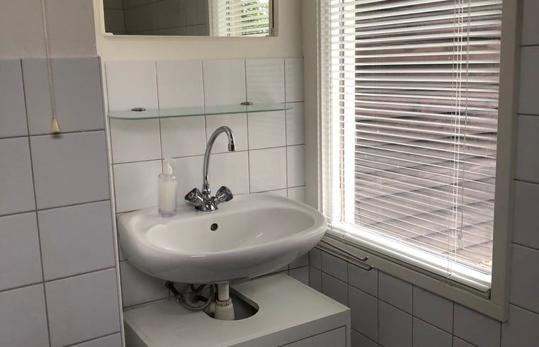 Modernes Badezimmer in Cottage in Haaksbergen, Ferienhaus in Twente, Overijssel mit Waschbecken und natuerlichem Licht durch grosse Fenster.