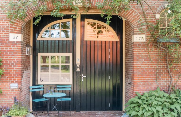 Entree van vakantiehuisje in Diepenheim, Twente, omgeven door groene planten.