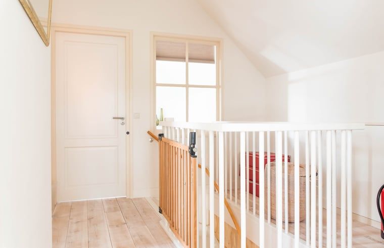 Lichte overloop in vakantiehuisje in Diepenheim met houten trap en moderne details.