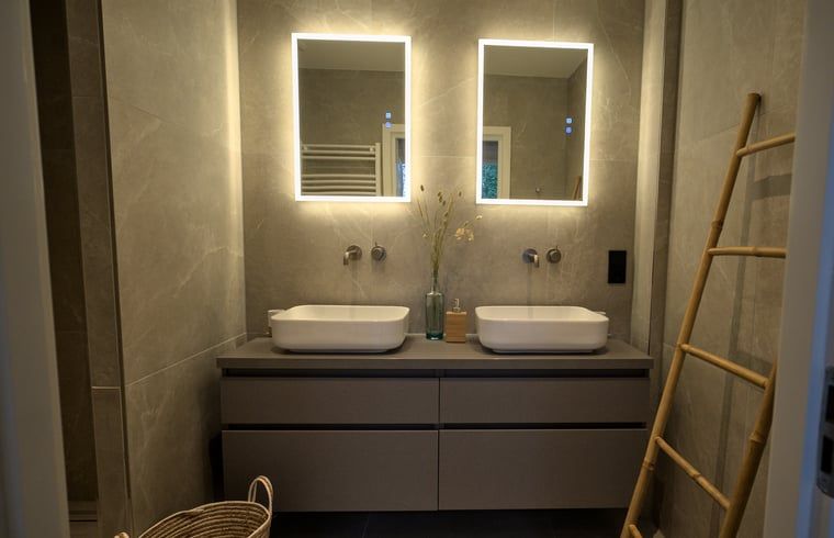 Moderne badkamer in Vakantiehuis in Oldenzaal, Twente, met dubbele wastafel en sfeerverlichting.