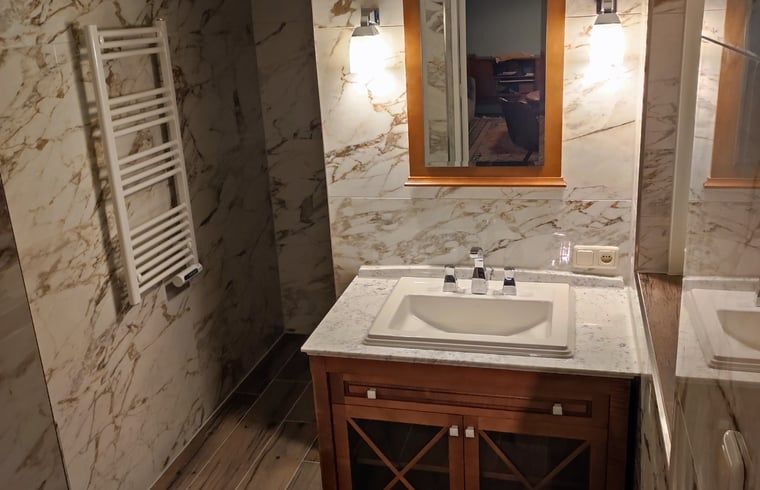 Luxurioeses Badezimmer in einem Ferienhaus in Oldenzaal, Twente, mit Marmorverkleidung und modernen Annehmlichkeiten.