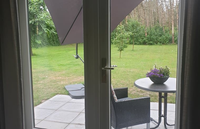 Veranda van Huisje in Westerhaar-Vriezenveensewijk, Twente, Overijssel, met uitzicht op groene tuin en comfortabele zitplek.