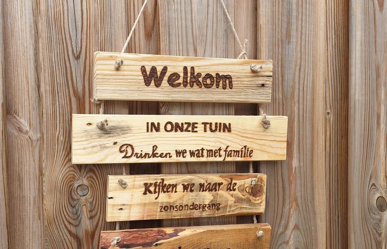 Welkomstbord in tuin van Huisje in Westerhaar-Vriezenveensewijk, Twente, dat gasten op charmante wijze verwelkomt.