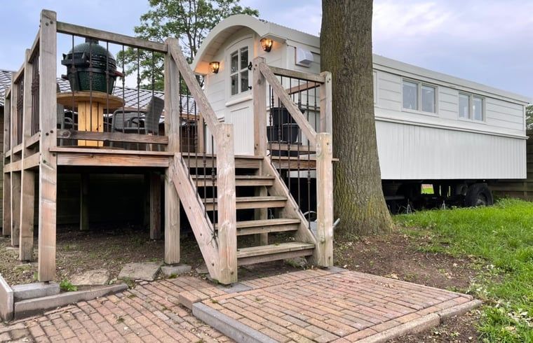 Verhoogd terras bij Vakantiehuisje in Markelo, Twente, Overijssel met houten trap en uitzicht op groene natuur.