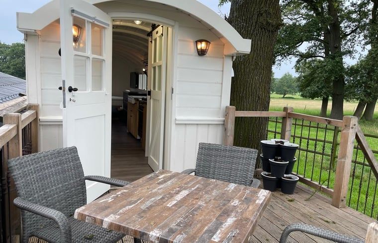 Buitenterras van Vakantiehuisje in Markelo, Twente, Overijssel met houten tafel en stoelen voor ontspanning.