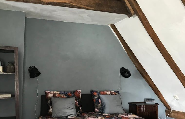 Sfeervolle slaapkamer in Vakantiehuisje in Markelo, Twente met rustieke houten balken en comfortabele bedden, perfect voor een ontspannen verblijf.
