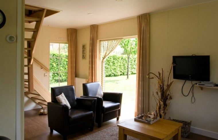 Geraeumiges Interieur des Ferienhauses in Enter, Twente, Overijssel, mit moderner Treppe und Gartenblick.