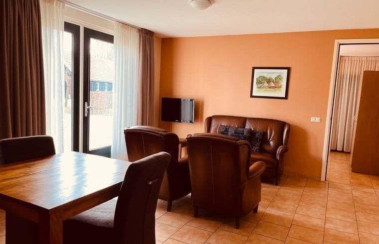 Gemuetliches Wohnzimmer im Ferienhaus in Denekamp, Twente, mit komfortabler Sitzecke und Essecke, ideal fuer entspannte Familienurlaube.