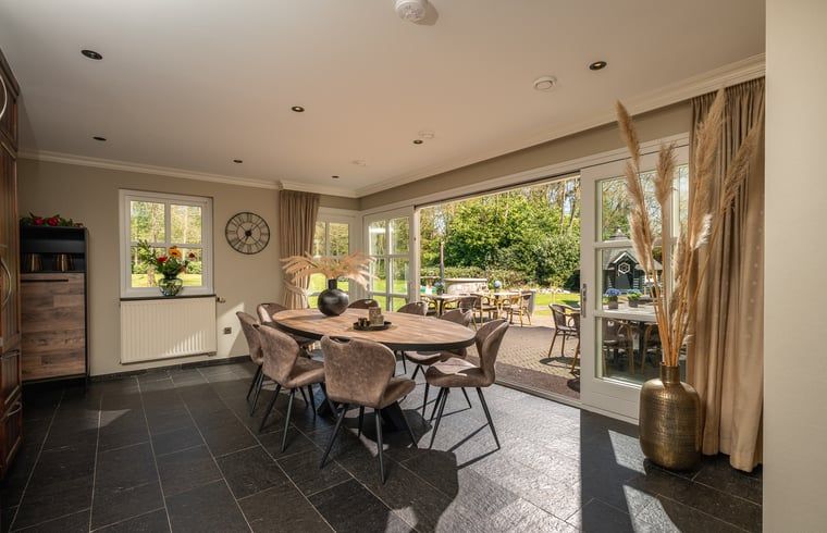 Gezellige eetruimte in Huisje in Losser, vakantiehuis in Twente, Overijssel met uitzicht op de groene tuin en terras.