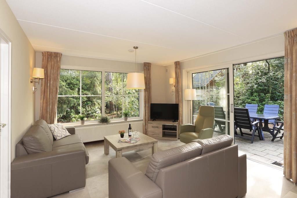 Cozy living room in Boshuus Comfort Plus vacation home in Deurningen, Twente, overlooking green nature.