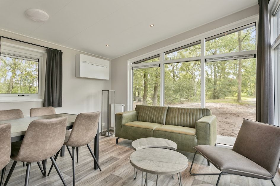 Cozy living room of vacation home IJssel 6 in Hoge Hexel, Twente, Overijssel with views of green nature through large windows.