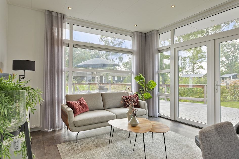 Helles Wohnzimmer im Ferienhaus Regge 4, Hoge Hexel, Twente mit Blick auf die Terrasse und die gruene Umgebung.