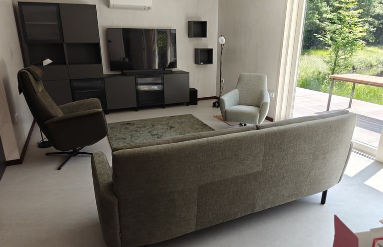 Cozy living room in Cottage in Buurse, vacation home in Twente, with comfortable seating and large windows.