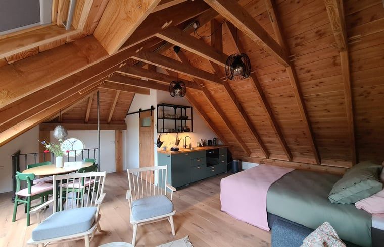 Gezellige binnenruimte van Vakantiehuisje in Hengevelde, Twente met houten balken en zithoek.