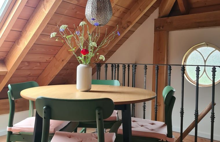 Eethoek in Vakantiehuisje in Hengevelde, Twente met ronde tafel en bloemenvaas.