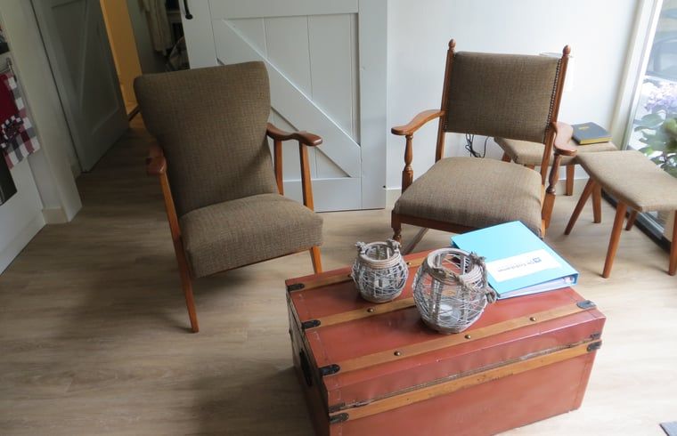 Stilvoller Innenraum im Ferienhaus in Boekelo, Enschede, mit bequemen Stuehlen und einer rustikalen Truhe.