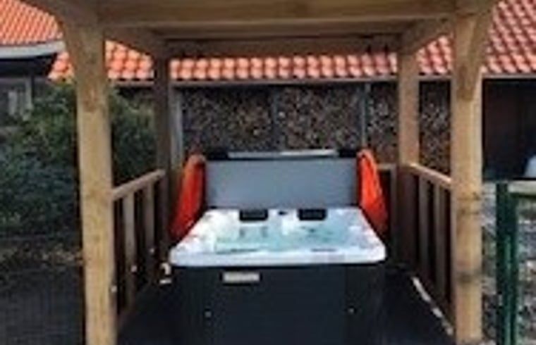 Der ueberdachte Jacuzzi im Ferienhaus in Boekelo, Twente, bietet luxurioese Entspannung im Freien.
