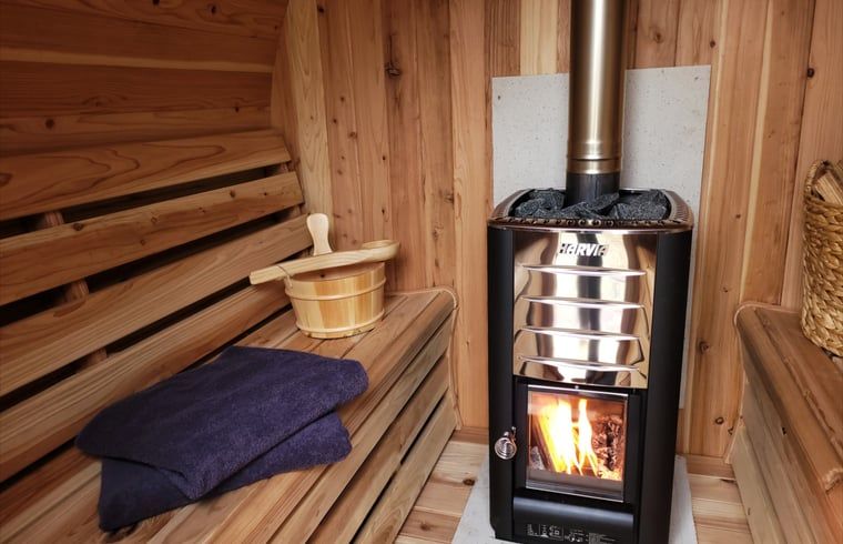 Helles Wohnzimmer im Ferienhaus in Lonneker, Twente, mit bequemem Sofa und Blick auf die Natur von Overijssel.