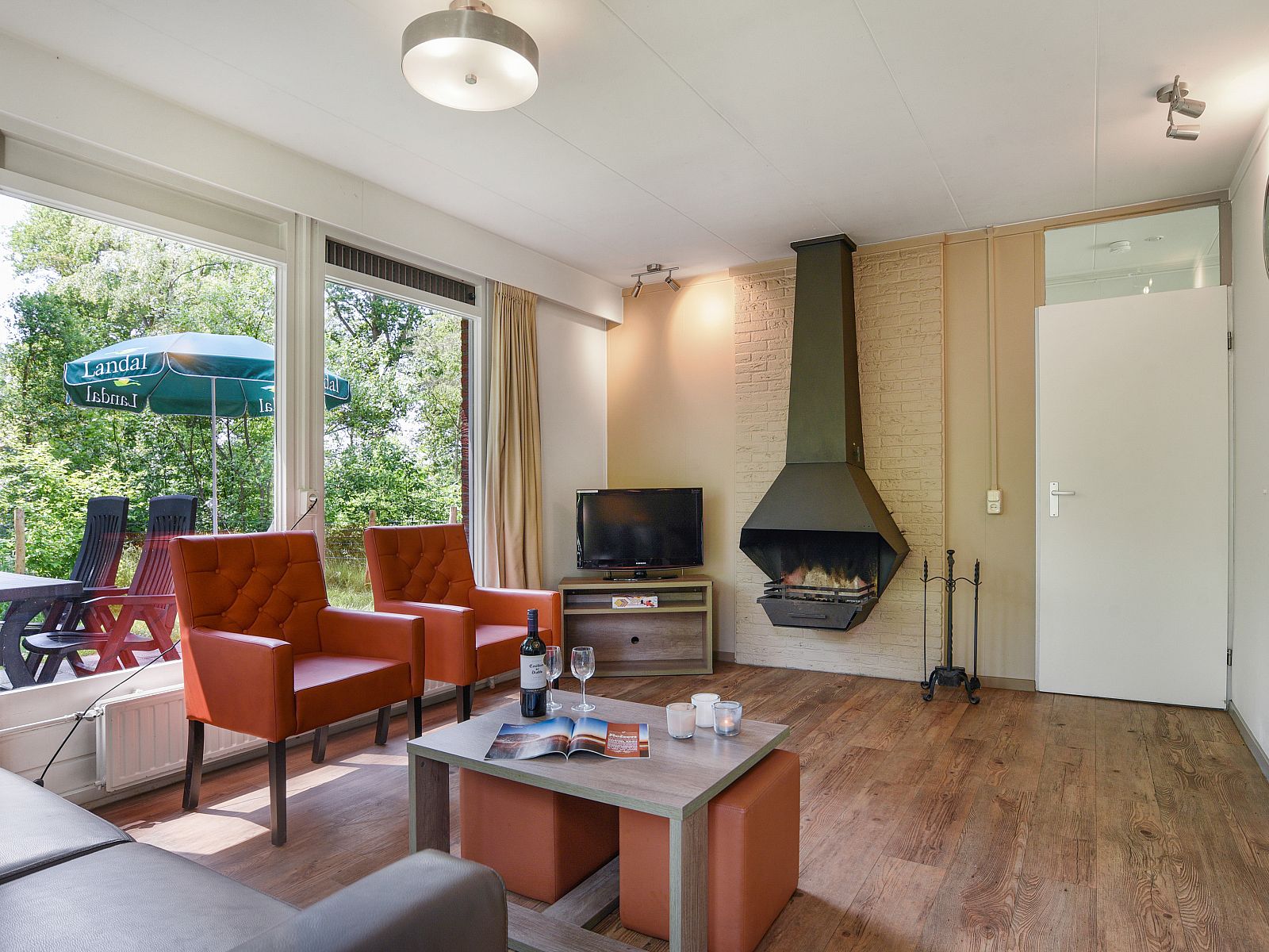 Bright living room overlooking terrace in Twenhaarsveld dog bungalow, Holten, surrounded by greenery.
