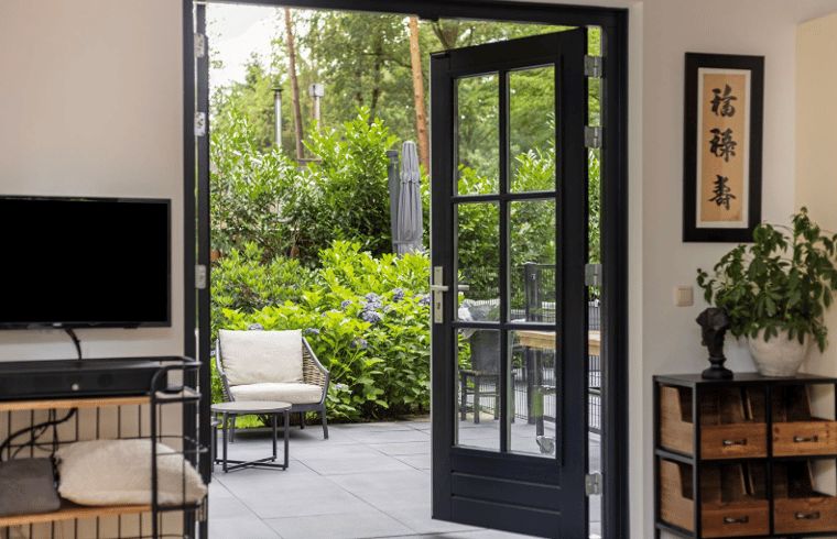 Gemuetlicher Innenbereich des Huisje in Holten mit Fluegeltueren zu einer sonnigen Terrasse, gelegen im gruenen Salland, Overijssel.