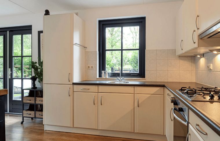 Moderne Kueche im Huisje in Holten, einem Ferienhaus im gruenen Salland, Overijssel, mit Blick aus dem Fenster auf den Garten.