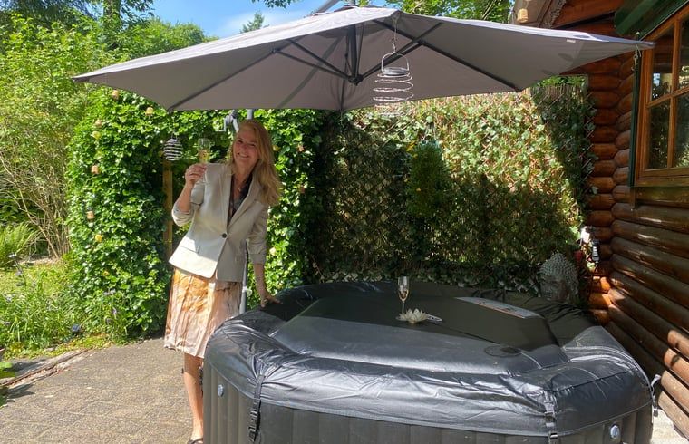 Geniet van ontspanning in de tuin van Vakantiehuisje in Holten, gelegen in het groene Salland, Overijssel, met een luxe jacuzzi onder een parasol.
