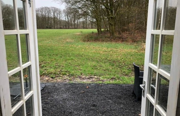 Uitzicht vanuit Vakantiehuisje in Wijhe, Salland op groene velden en bosrijke omgeving.
