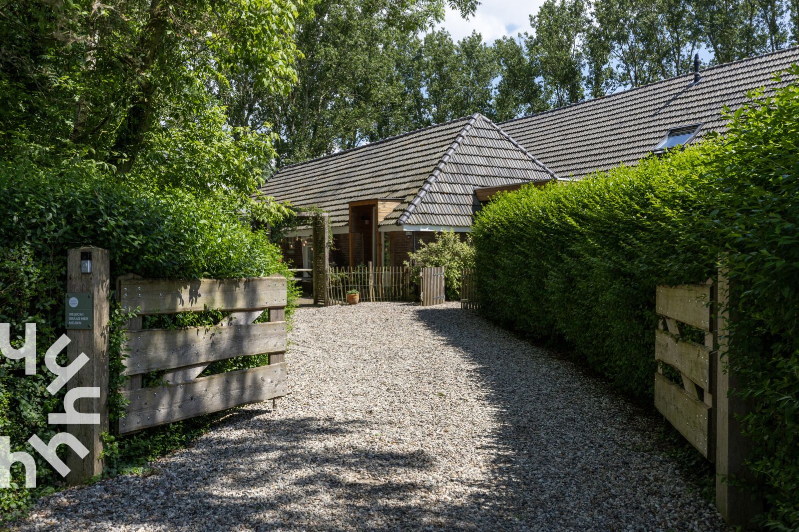 Ingang van OV529 vakantiehuis in Zwolle, Salland, met grindpad en houten hek.